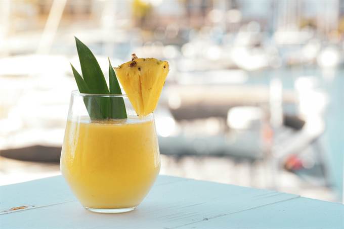 Suco de abacaxi em copo com fatia da fruta na borda