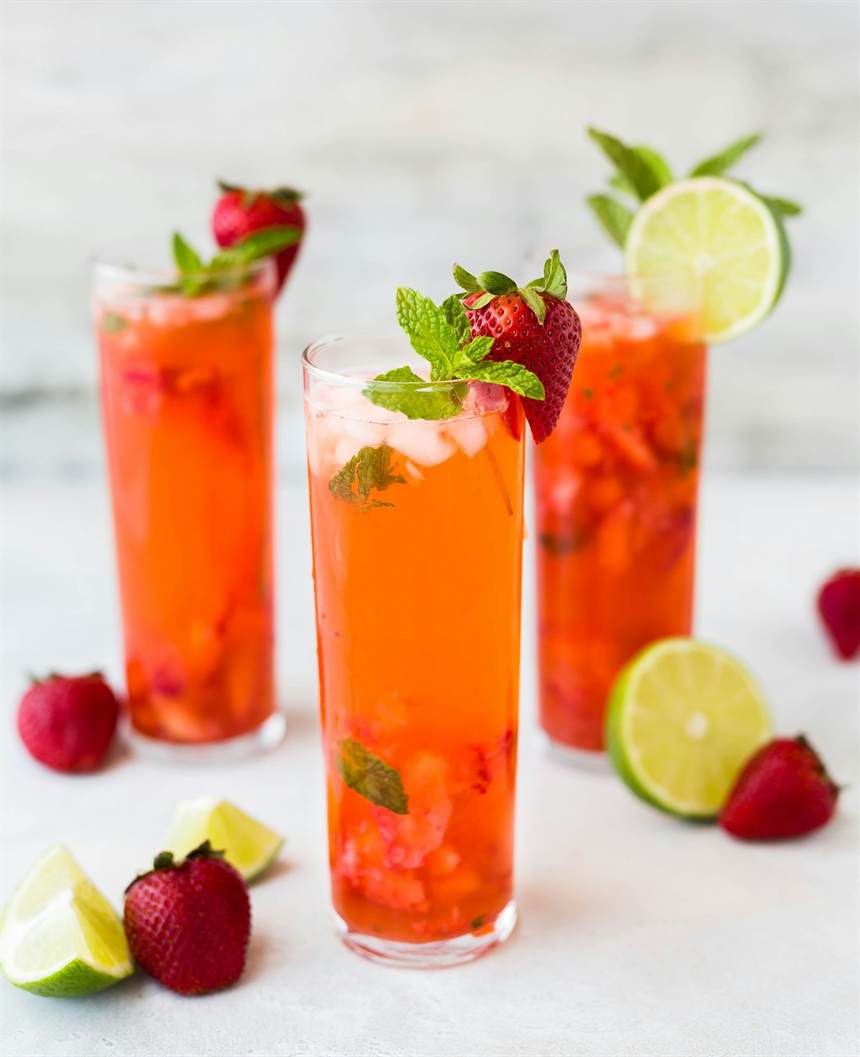 Copos de suco de morango com limão e hortelã sobre bancada clara