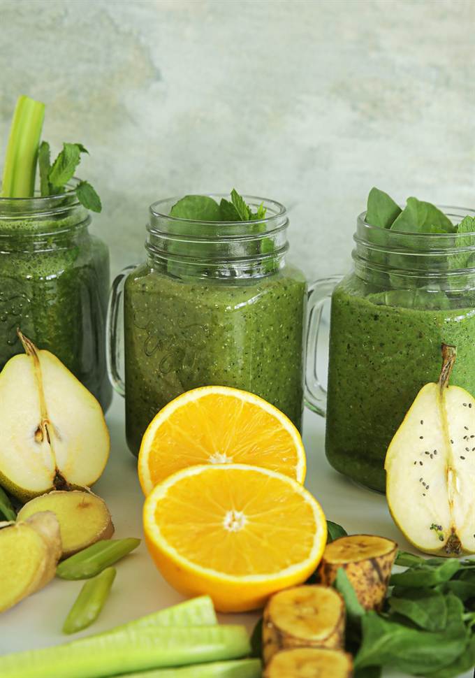 Potes de suco natural ao lado de frutas e legumes frescos